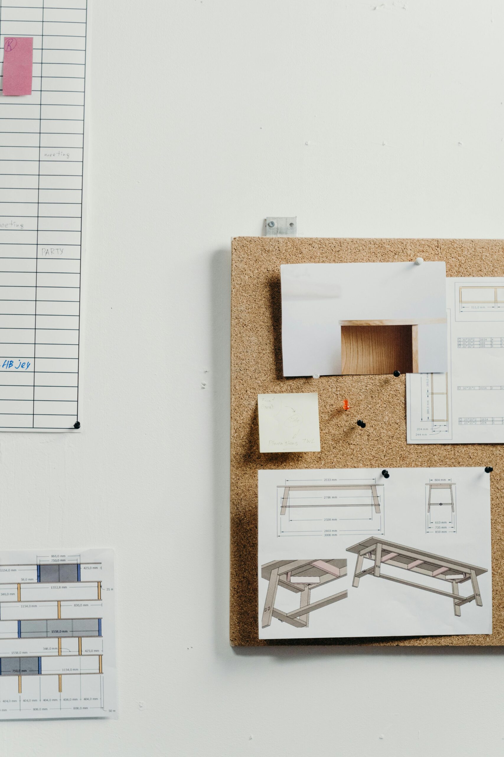 Corkboard displaying architectural drawings in a minimalist office setting.